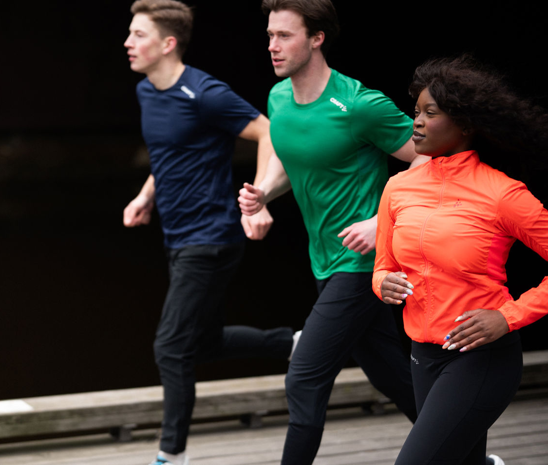 Tre personer som løper i fargerike sportsklær - blå, grønn og oransje treningsklær